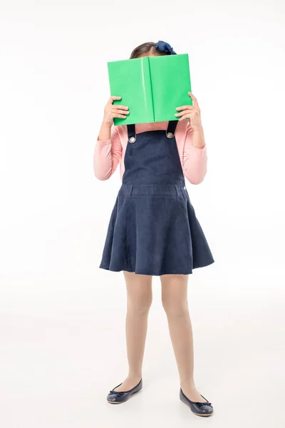 Schoolgirl hiding face with book — Stock Photo