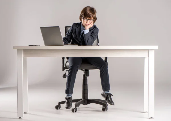 Niño en traje de negocios con la mano en la barbilla - foto de stock