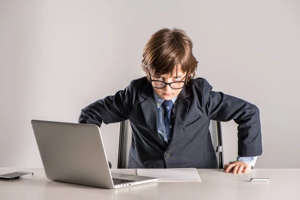 Niño de escuela en traje de negocios de pie sobre el escritorio - foto de stock