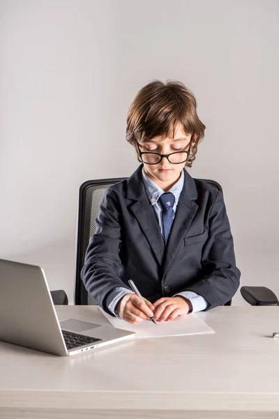 Schoolchild in business suit writing documents — Stock Photo