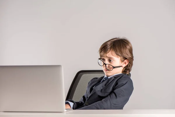 Schulkind im Businessanzug schaut auf Laptop — Stockfoto