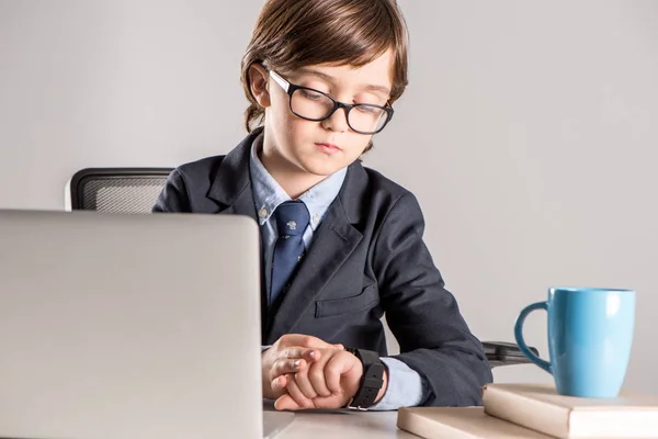 Niño de escuela en traje de negocios mirando smartwatch - foto de stock