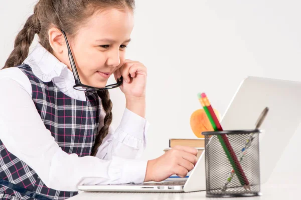 Colegiala en el escritorio con portátil - foto de stock