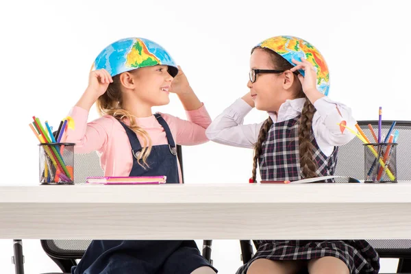 Schoolgirls with halves of globe on heads — Stock Photo
