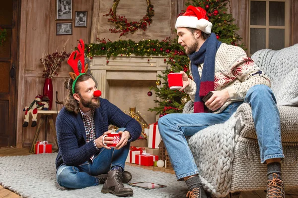 Los hombres en trajes de Navidad beber té - foto de stock