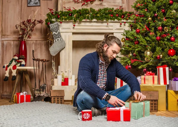 Мужчина, сидящий с рождественскими подарками — стоковое фото