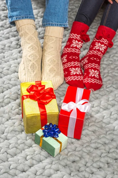 Beine in gestrickten Socken und Weihnachtsgeschenken — Stockfoto