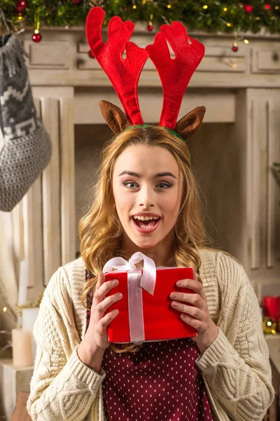 Surprised woman holding christmas present — Stock Photo