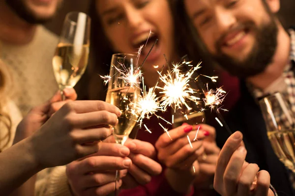 Des gens avec des verres de champagne et des étincelles — Stock Photo