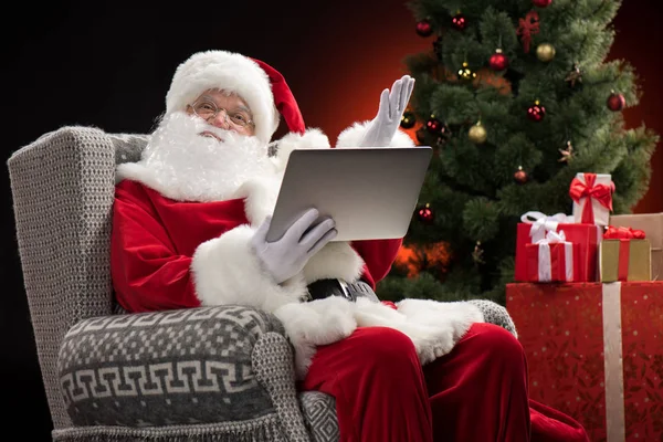 Санта-Клаус с помощью ноутбука и жеста — стоковое фото