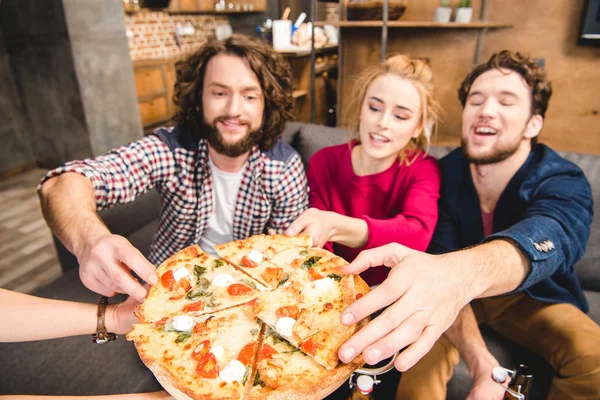 Amici sorridenti che assaggiano pizza — Foto Stock