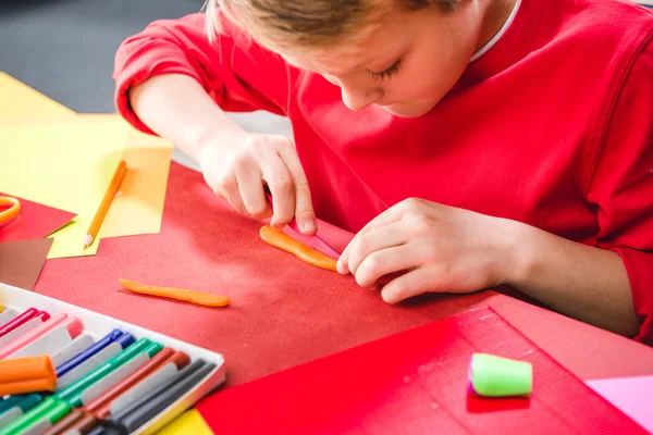 Schoolchild cutting plasticine — Stock Photo, Image