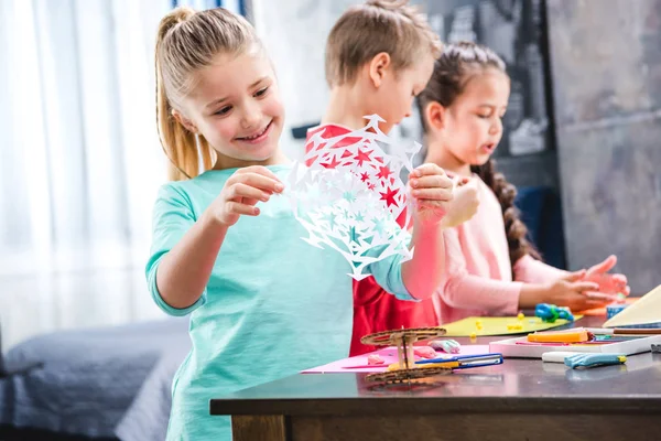 Kind schneidet Schneeflocke aus Papier — Stockfoto