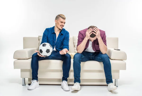 Friends sitting on couch with soccer ball — Stock Photo, Image
