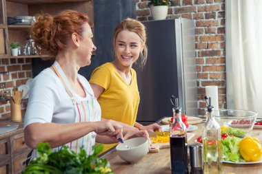 Mother and daughter cooking together clipart