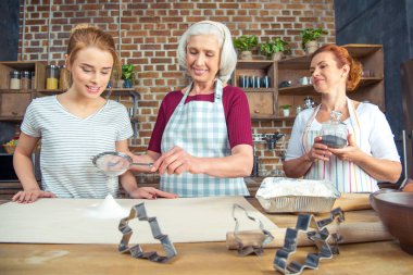 Grandmother and granddaughter sifting flour clipart