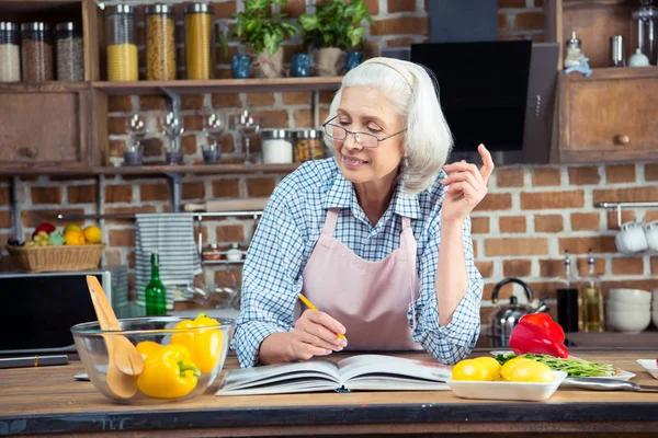 Senior woman with cookbook — Stock Photo, Image