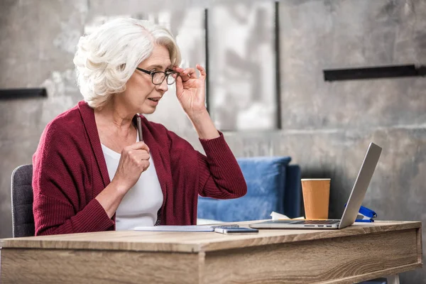 Senior woman adjusting eyeglasses — Stock Photo, Image