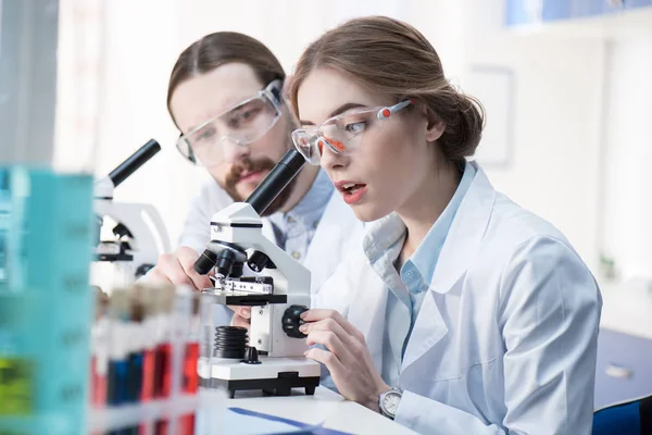 Químicos trabajando con microscopio — Foto de Stock