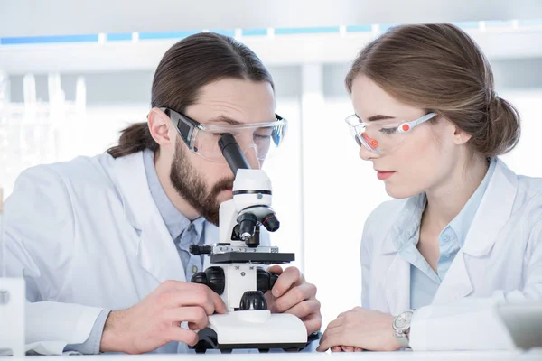 Químicos trabajando con microscopio — Foto de Stock