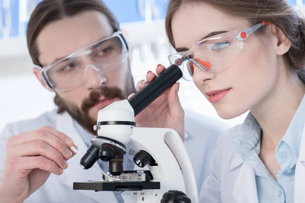 Químicos trabajando con microscopio — Foto de Stock