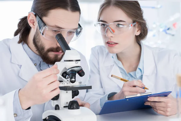 Chemists working with microscope — Stock Photo, Image