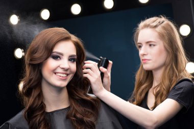 Hairdresser fixing hair of model  clipart
