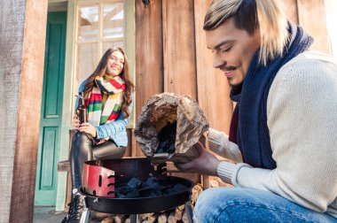 Man filling grill with charcoal clipart