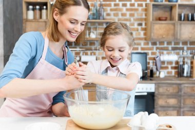 Mother and daughter preparing dough clipart