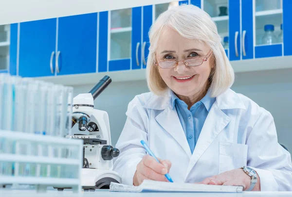 Químicos senior escribiendo en bloc de notas — Foto de Stock