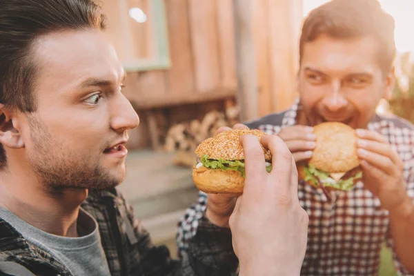 Hombres comiendo hamburguesas — Foto de Stock