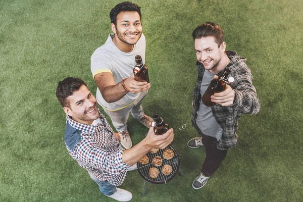 Amigos bebendo cerveja e fazendo churrasco — Fotografia de Stock