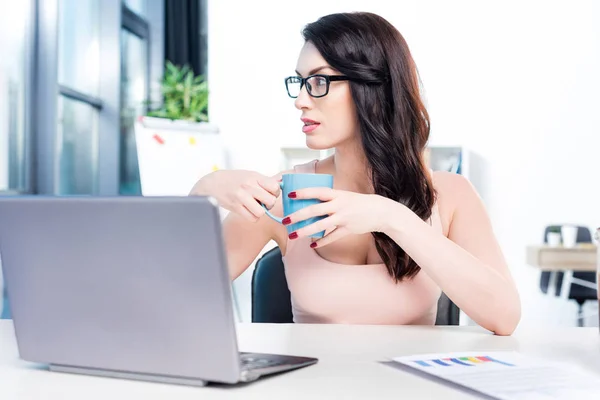 Businesswoman with coffee and laptop — Free Stock Photo