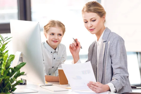 Business woman with daughter working in office — стоковое фото