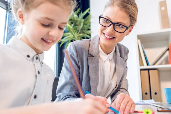 Daughter drawing with mother in office — Stock Photo, Image