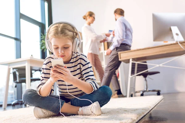 Filha usando smartphone e fones de ouvido — Fotografia de Stock