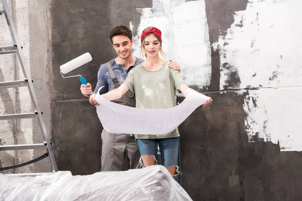 Couple with schemes and paint roller — Stock Photo, Image