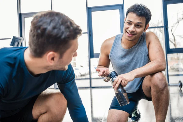 Hombre con botella de agua descansando en el gimnasio —  Fotos de Stock