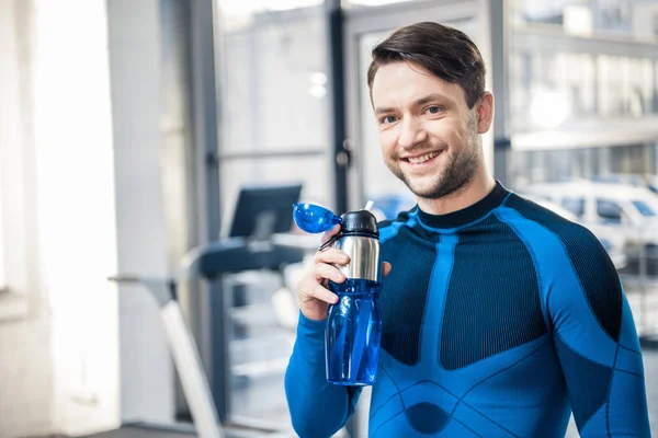 Человек с бутылкой воды в тренажерном зале — стоковое фото