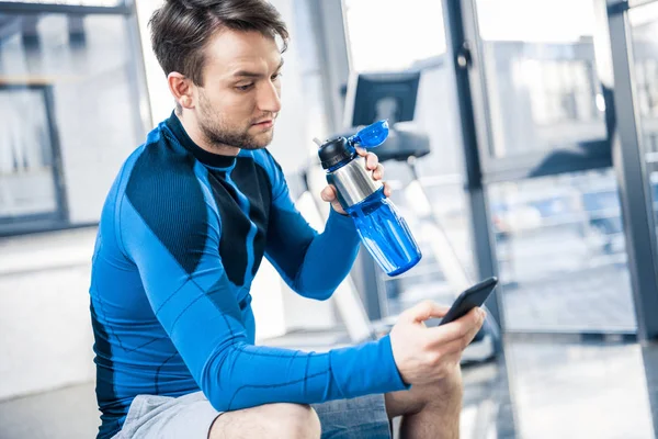 Ο άνθρωπος χρησιμοποιώντας το smartphone στο γυμναστήριο — Φωτογραφία Αρχείου
