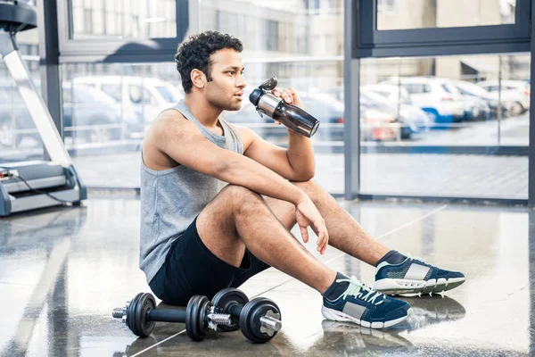 Άνθρωπος με μπουκάλι νερό που αναπαύεται στο γυμναστήριο — Φωτογραφία Αρχείου