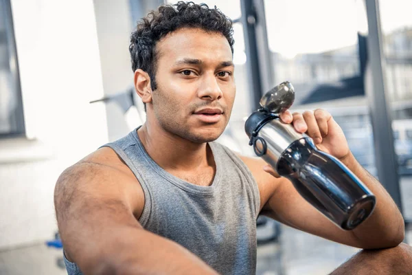 Hombre con botella de agua descansando en el gimnasio — Foto de Stock