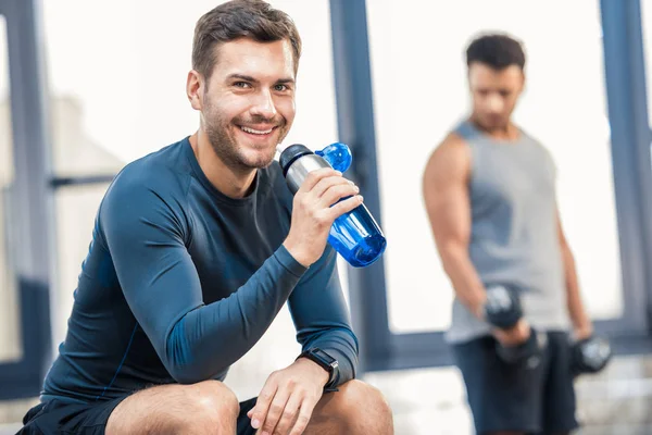 Mannen med flaska vatten vilar på gym — Stockfoto