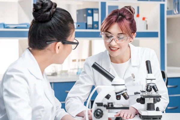 Cientistas que trabalham em conjunto com microscópios — Fotografia de Stock