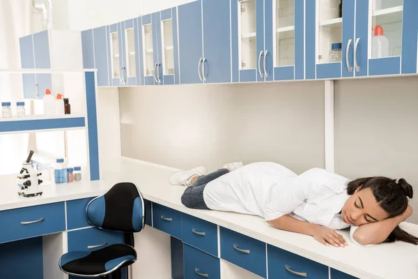 Flicka vetenskapsman sover på bordet i laboratorium — Stockfoto