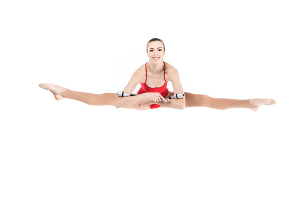 Woman rhythmic gymnast jumping with clubs — Stock Photo, Image