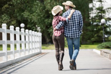 cowboy with girlfriend walking on pathway in park clipart
