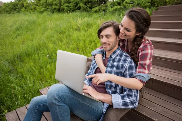 Para przy użyciu laptopa siedząc przy parku — Zdjęcie stockowe