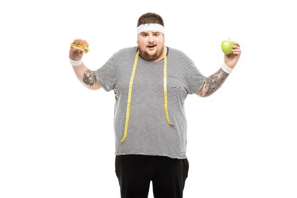 Gros homme tenant hamburger et pomme — Photo