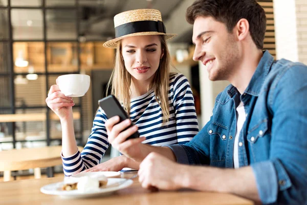 Пара, использующая смартфон в кафе — стоковое фото